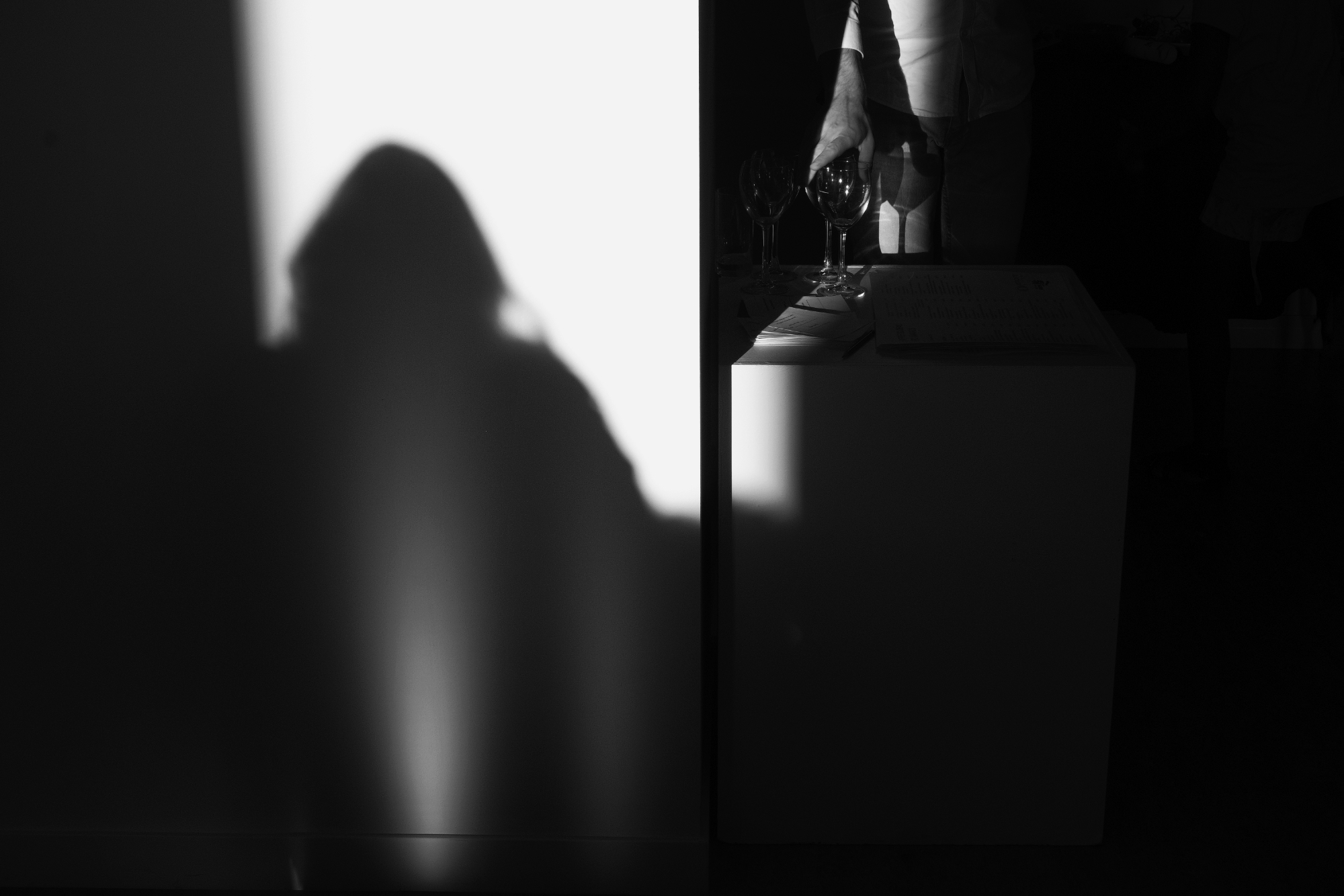 A shadowed hand reaching for a glass