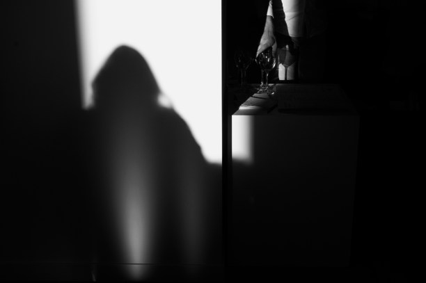 A shadowed hand reaching for a glass