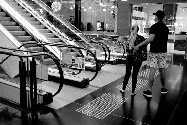 Photo of two people standing and the bottom of a set of escalators
