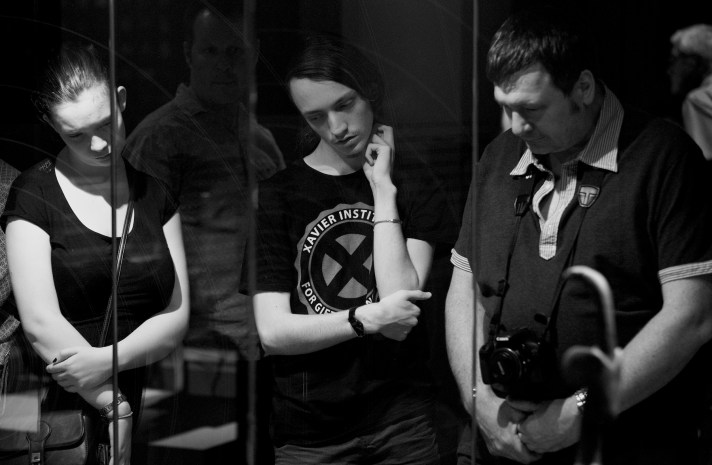 Three people looking down with another in the background looking over their shoulder