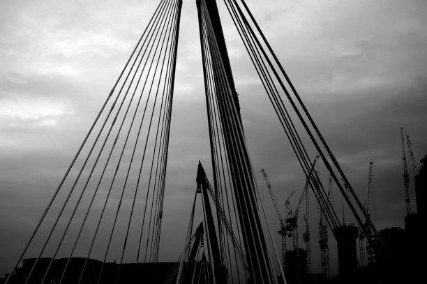 Photo of cranes and bridge structure against clouds