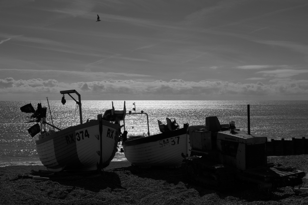 Photo of beached small fishing boats silhouetted against the sea
