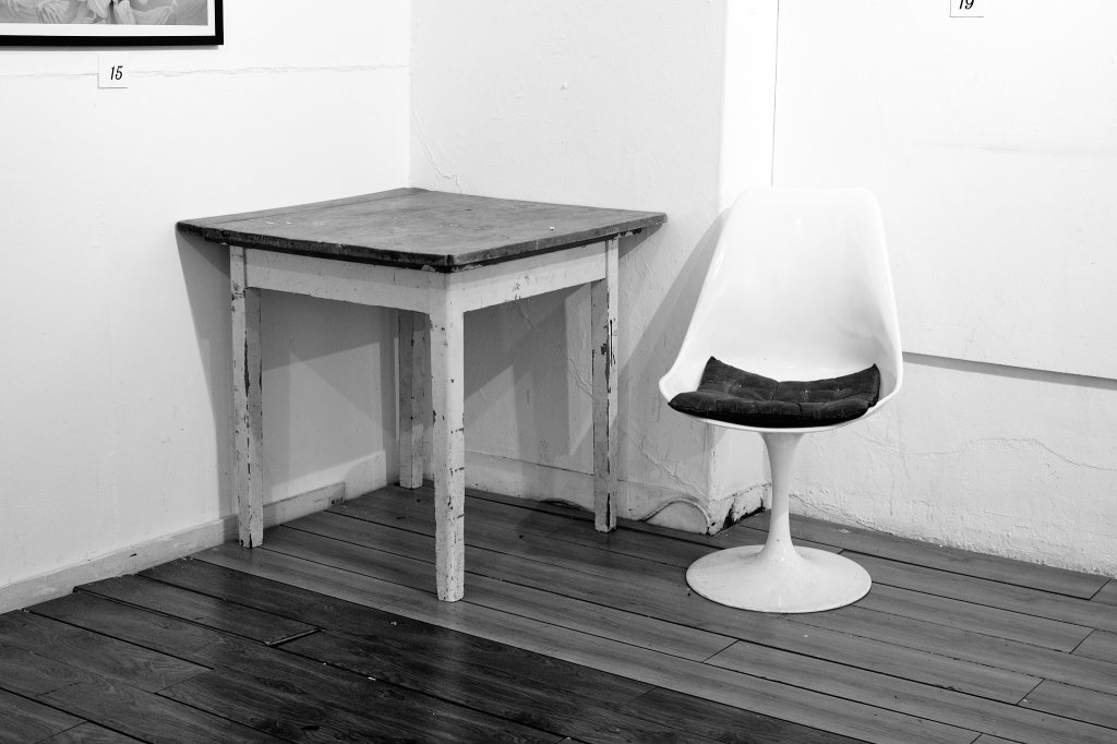 Image of a chair and table in a 'lesser' gallery.